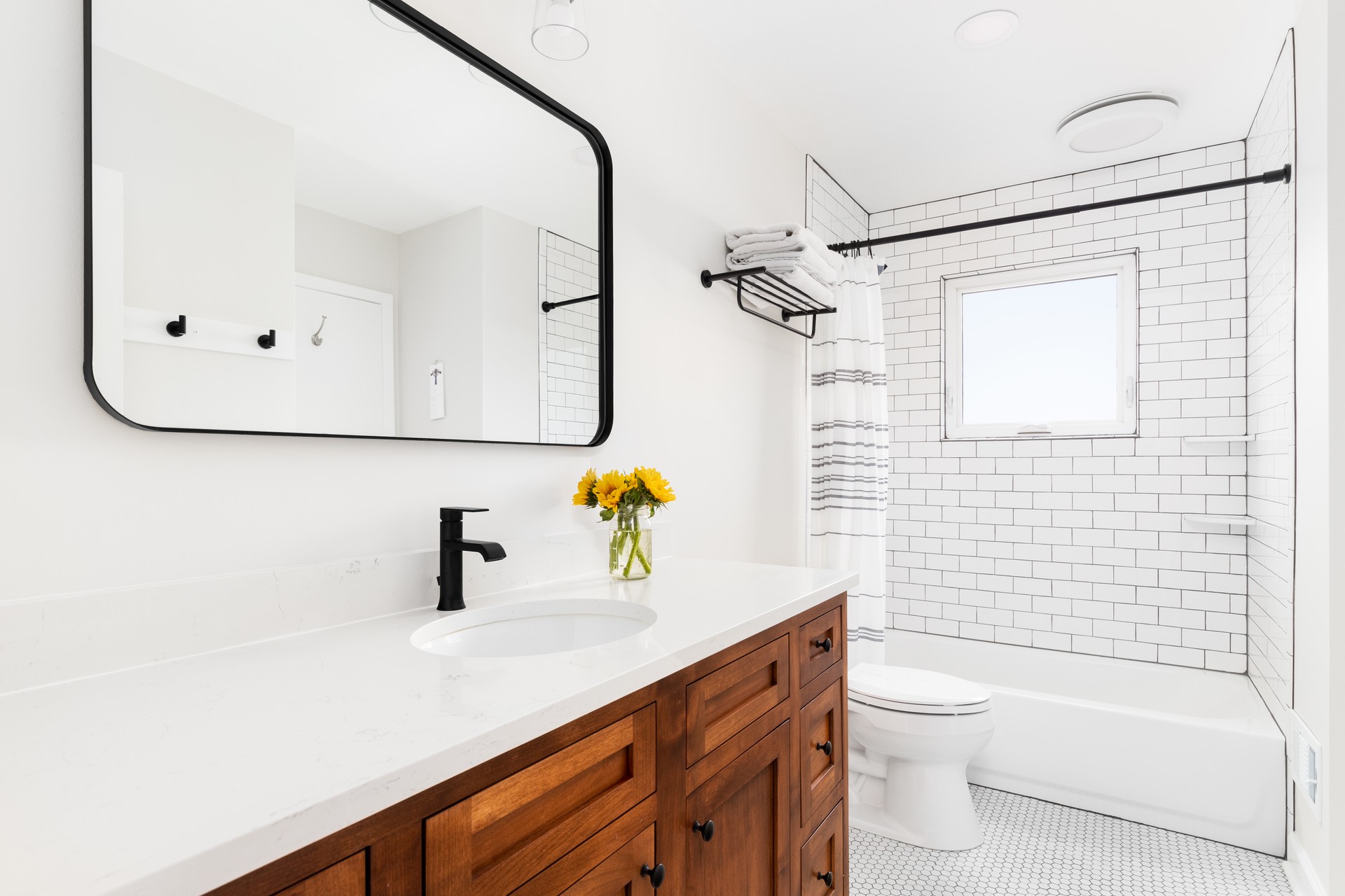 A farmhouse bathroom with a wood cabinet and subway tile shower.